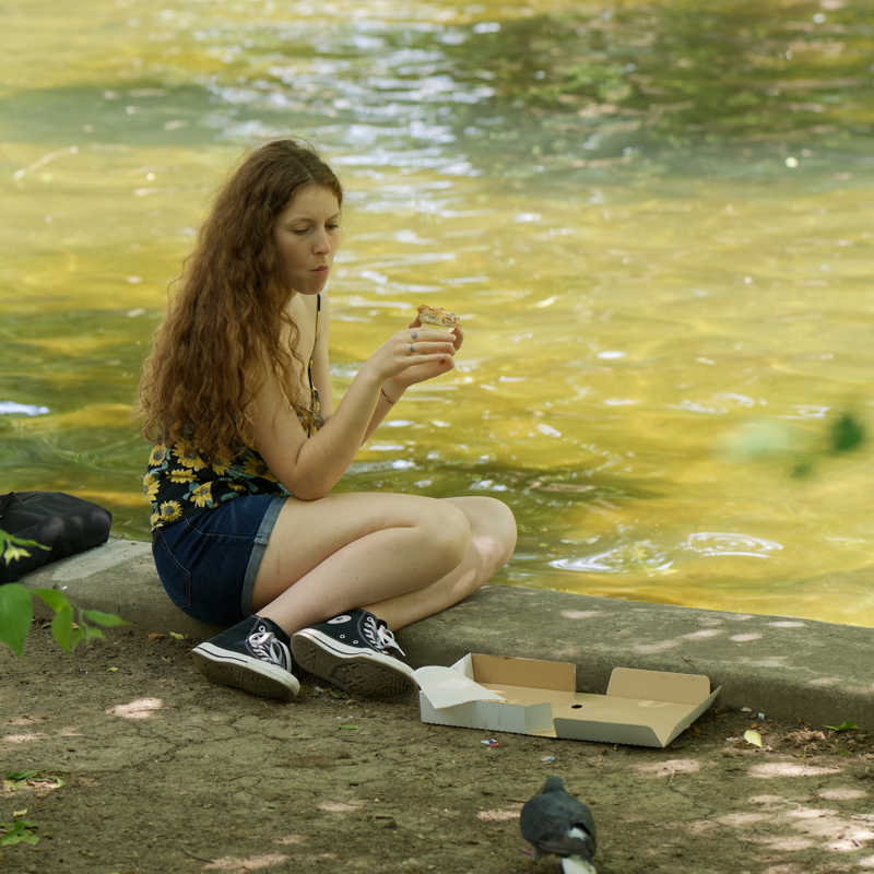 4 - Woman with long hair wearing a black tank top with a sunflower pattern, denim shorts, and black Converse sneakers
